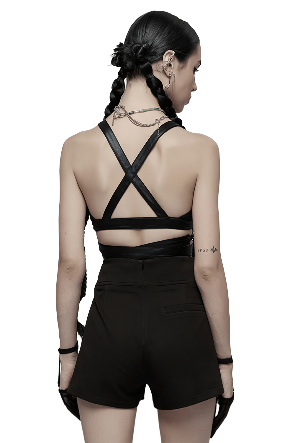 Back view of a model in a black punk crop top with crisscross straps and shorts, showcasing edgy style.