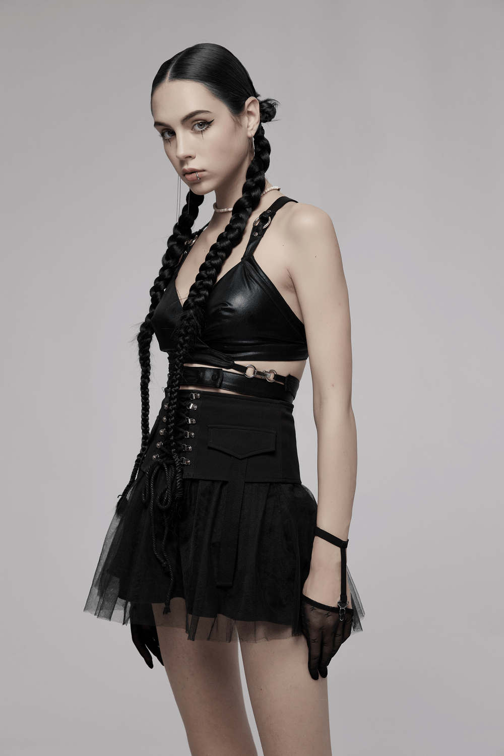 Model showcasing a black punk crop top with criss-cross back and layered tulle skirt, embodying edgy rock style.