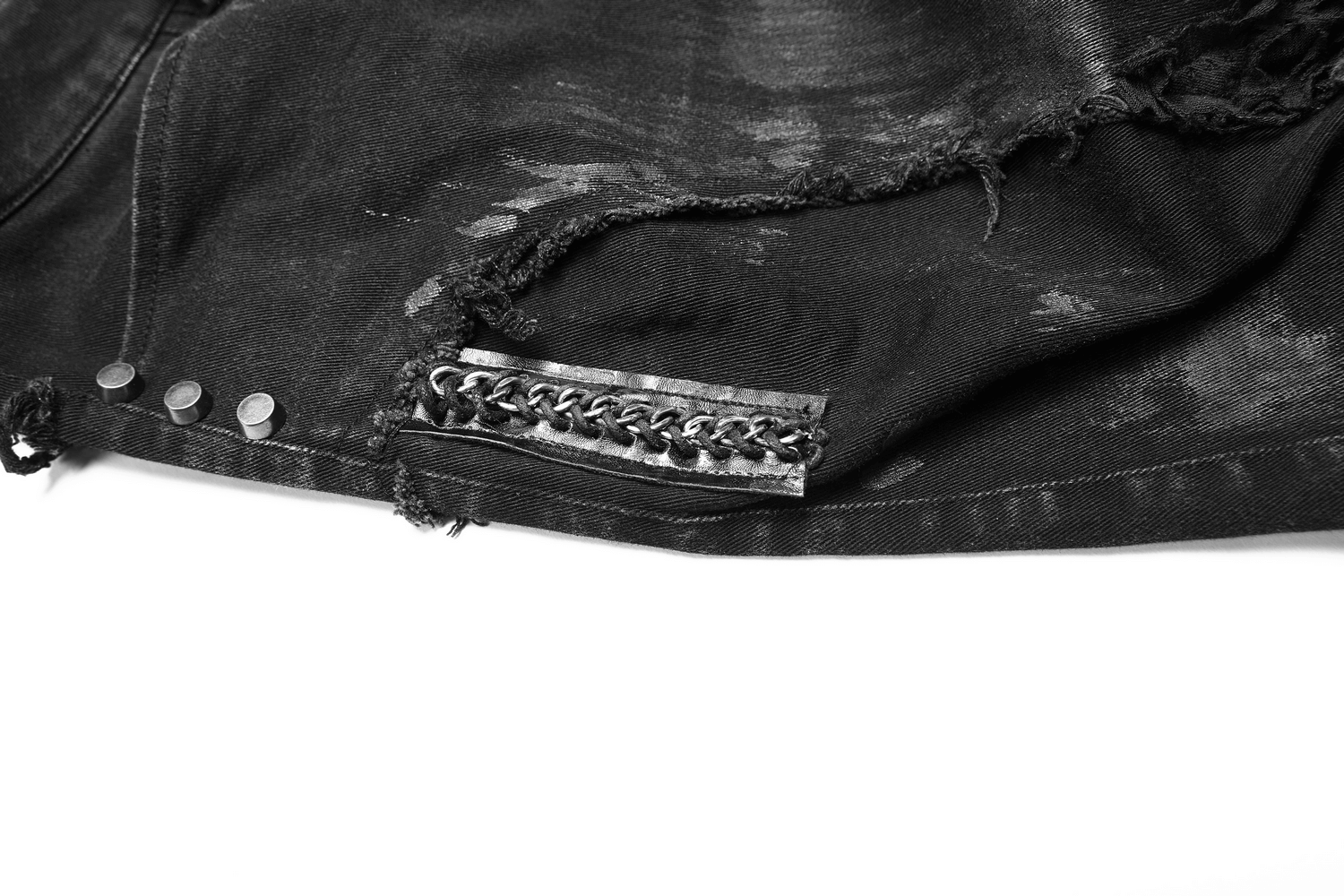 Close-up of black ripped jeans featuring fishnet layers and raw edges for a punk-style urban fashion statement.