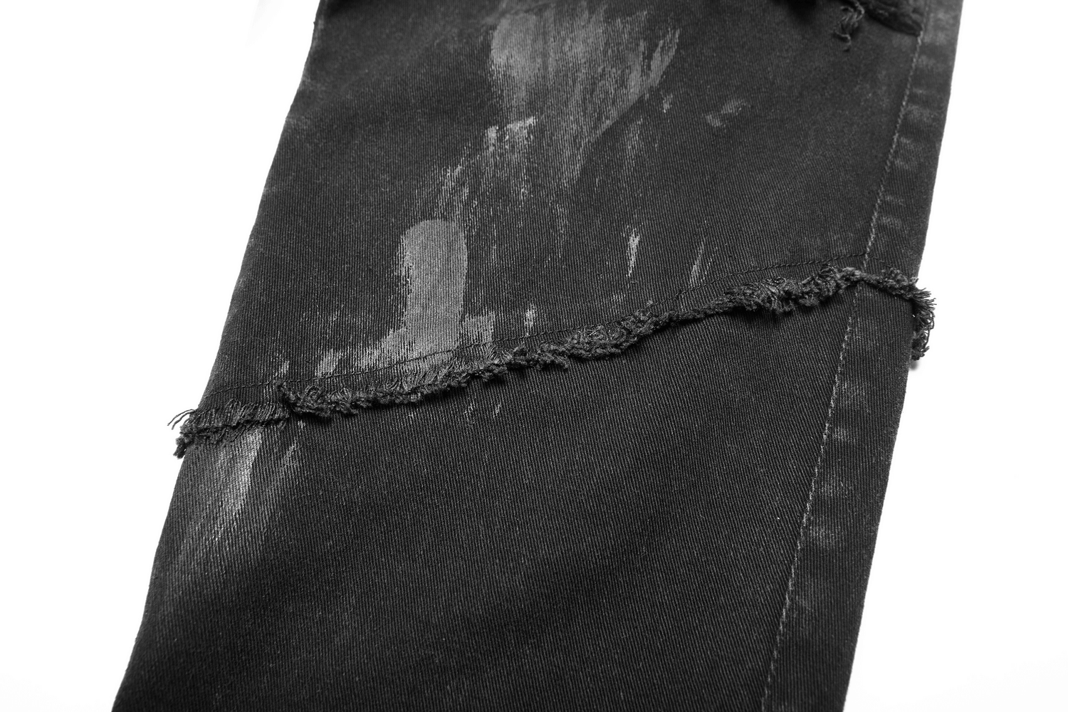 Close-up of black punk-style ripped jeans featuring raw edges and a distressed finish for an edgy urban look.