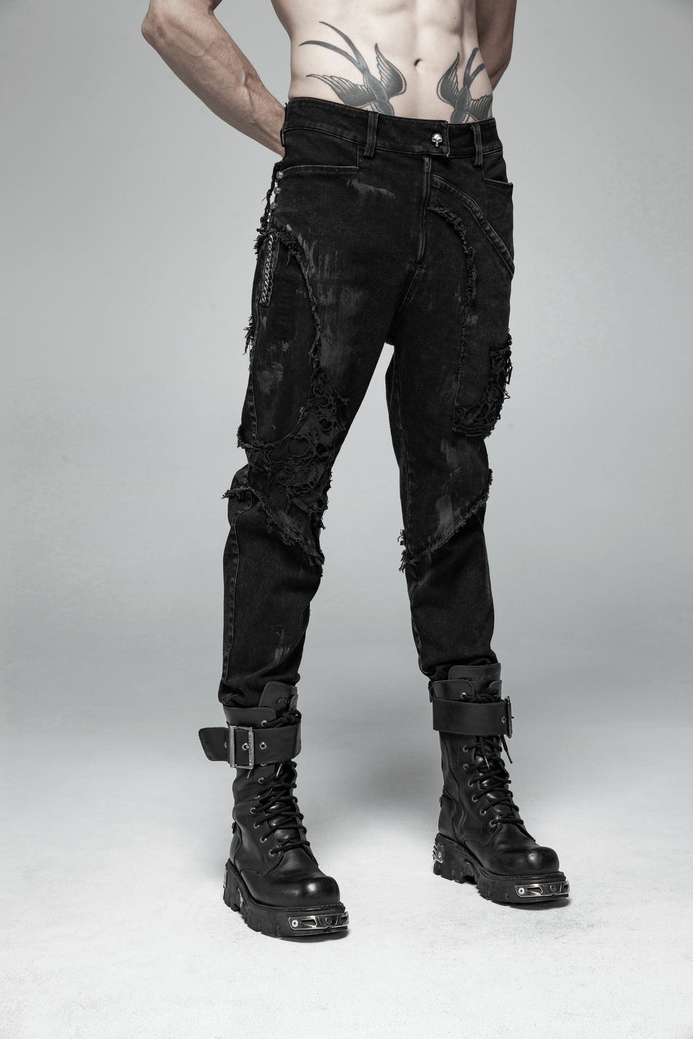 Punk-style black ripped jeans with fishnet layers, paired with edgy combat boots and a tattooed model.