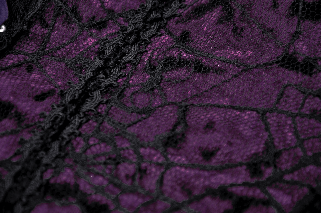 Close-up of black lace over purple fabric, showcasing intricate gothic lace details for a mini dress.