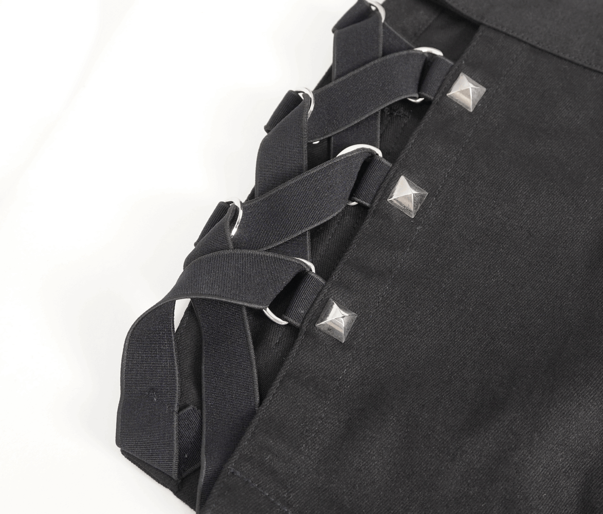 Close-up of black rave booty shorts with mesh garters, featuring silver studded details and adjustable straps.