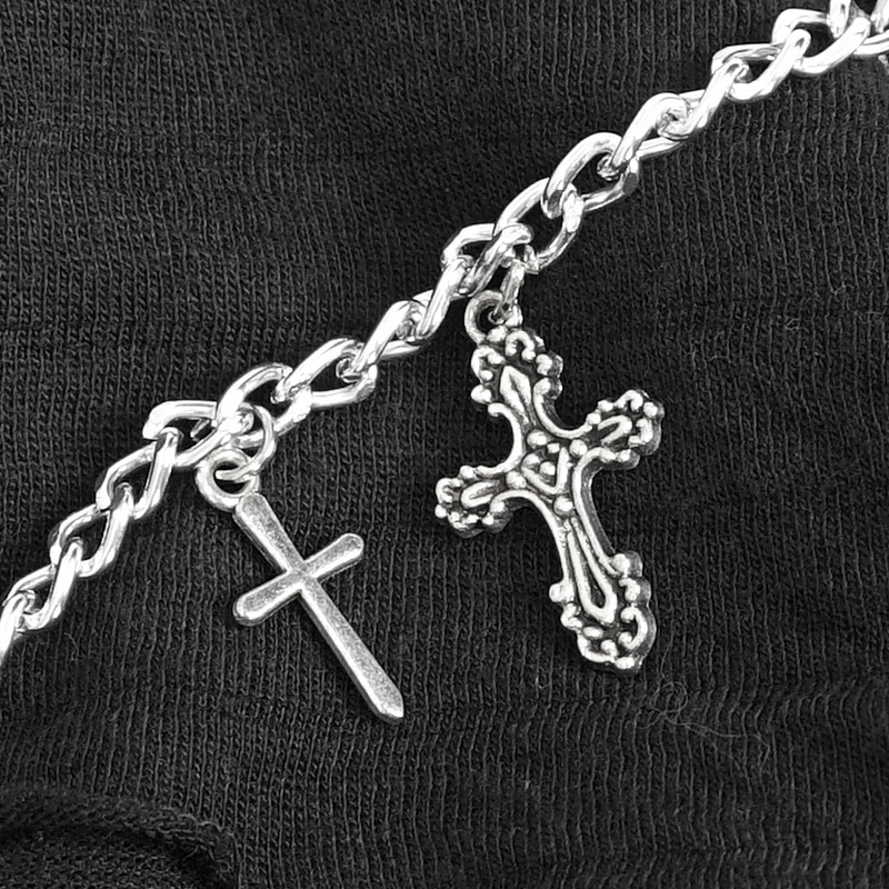 Silver chain with two cross charms on black fabric, adding punk and gothic vibes to fashion accessories.