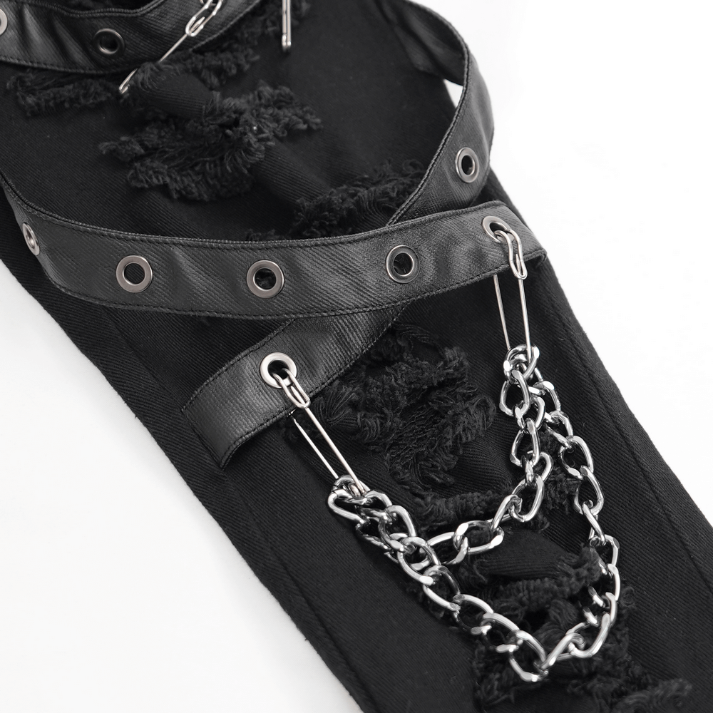 Close-up of black ripped skinny jeans featuring chains and leatherette buckles for an edgy gothic look.