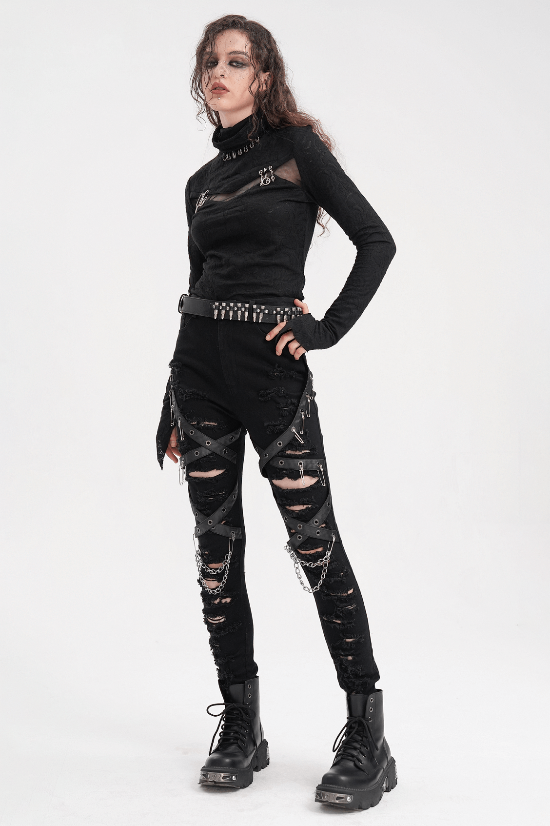 Edgy model in black ripped skinny jeans with chains and buckles, showcasing a rebellious gothic look.