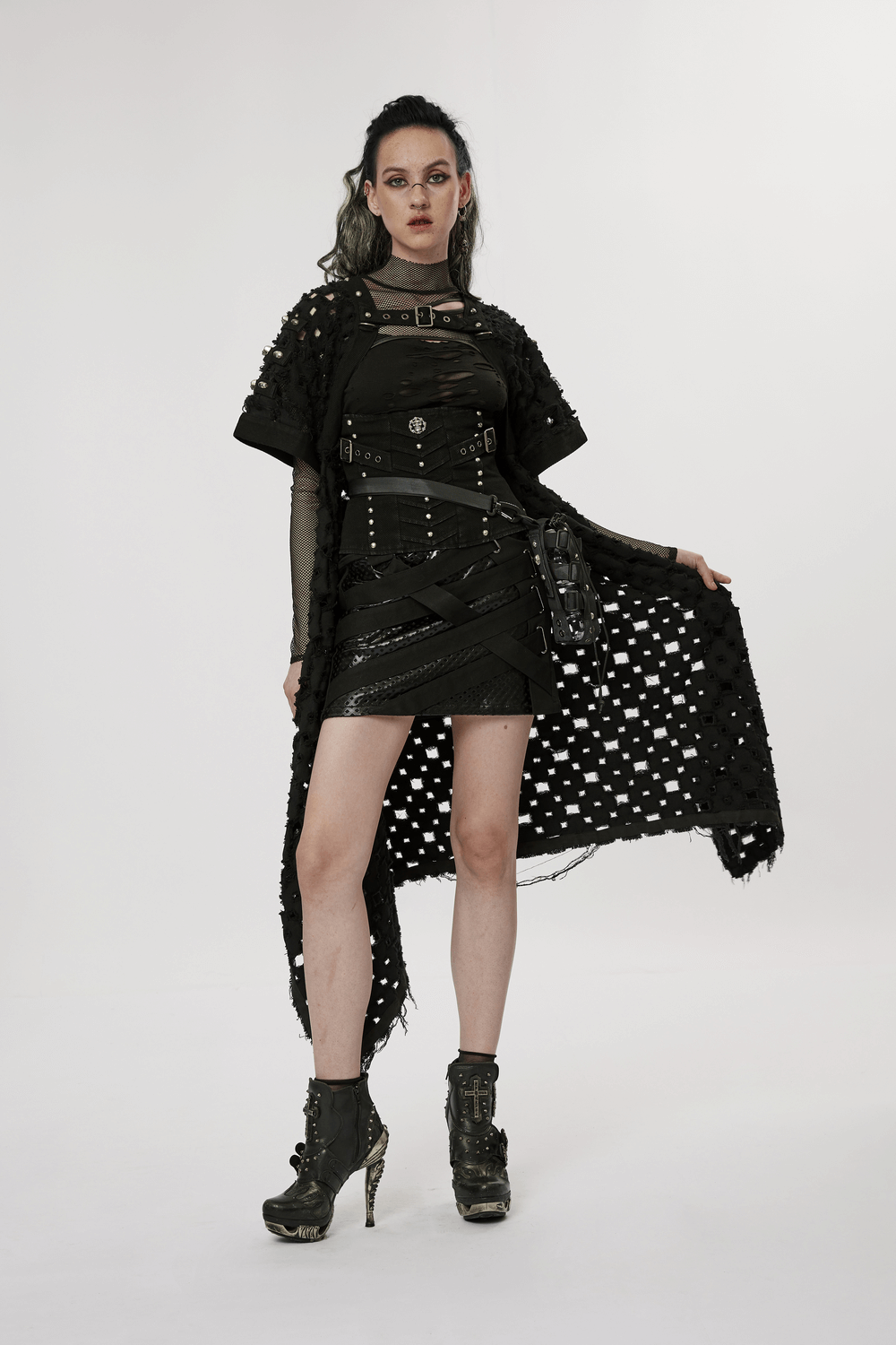 Post-apocalyptic style model in black ripped cardigan and edgy outfit with metal accents, showcasing alternative fashion.