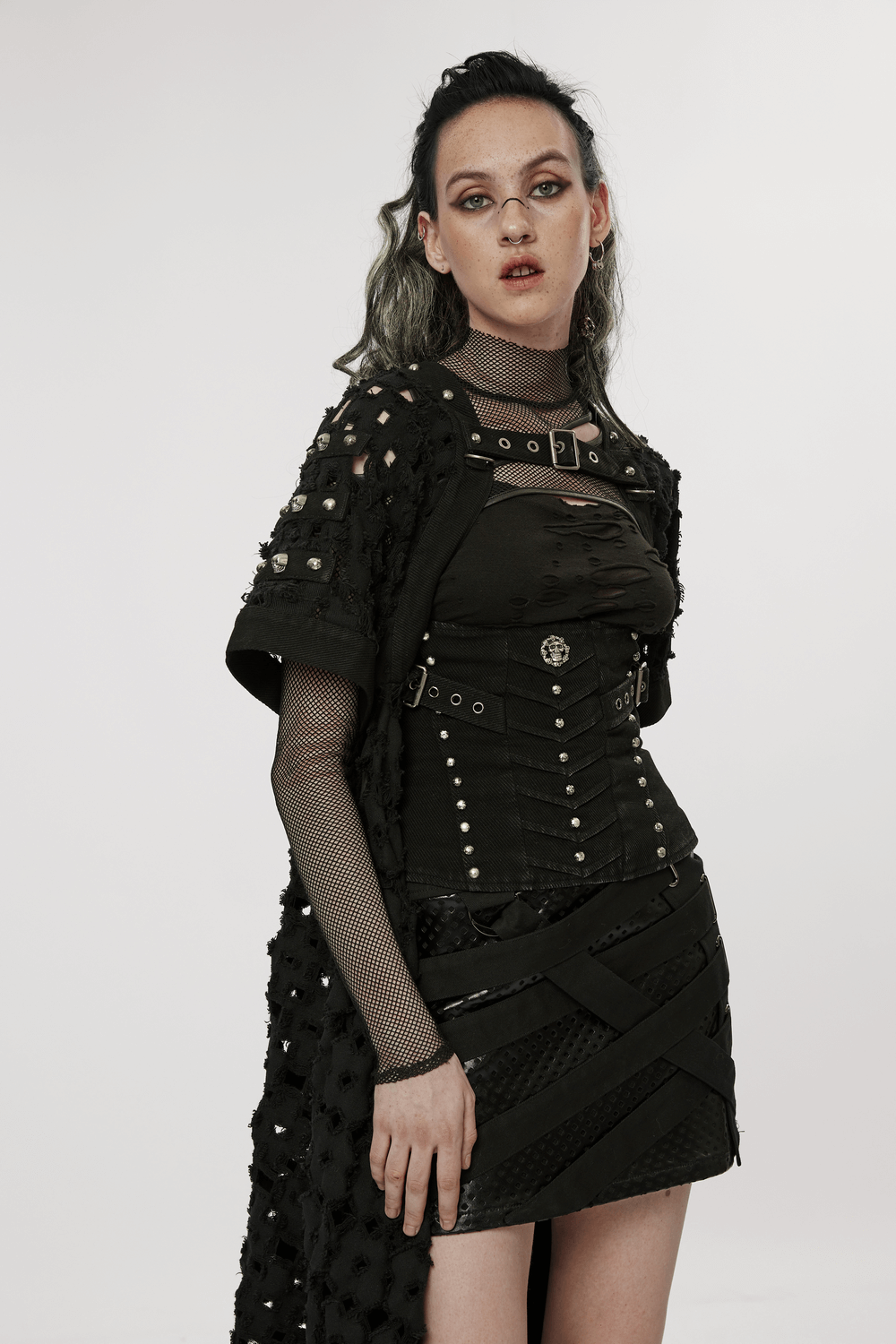 Fashion model showcasing a black ripped twill long cardigan-cape with skull rivets, embodying a post-apocalyptic warrior style.