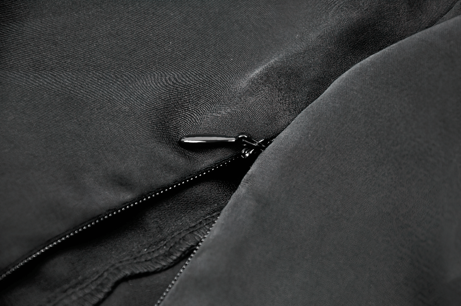 Close-up of black satin fabric showcasing a sleek zipper detail, perfect for gothic and alternative fashion.