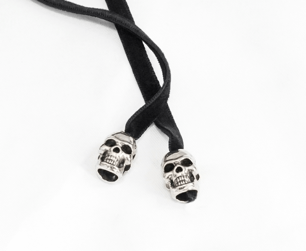 Black bolo tie with silver skull tips, adding a gothic flair to any outfit.