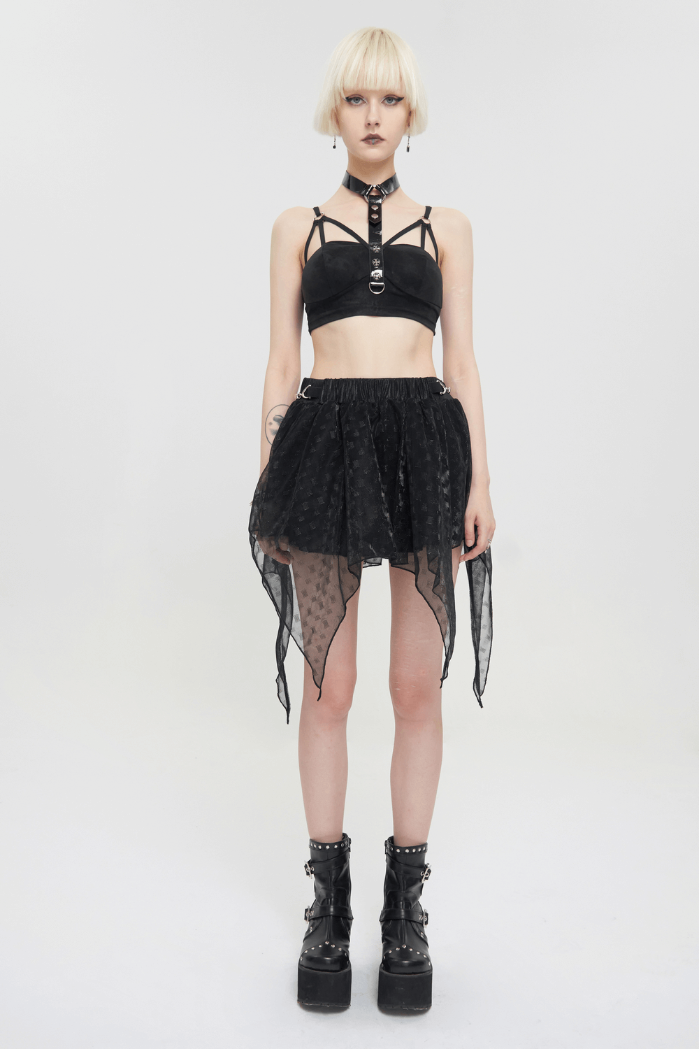 Fashionable model wearing a black gothic punk bra with faux leather straps and a flowy black skirt.
