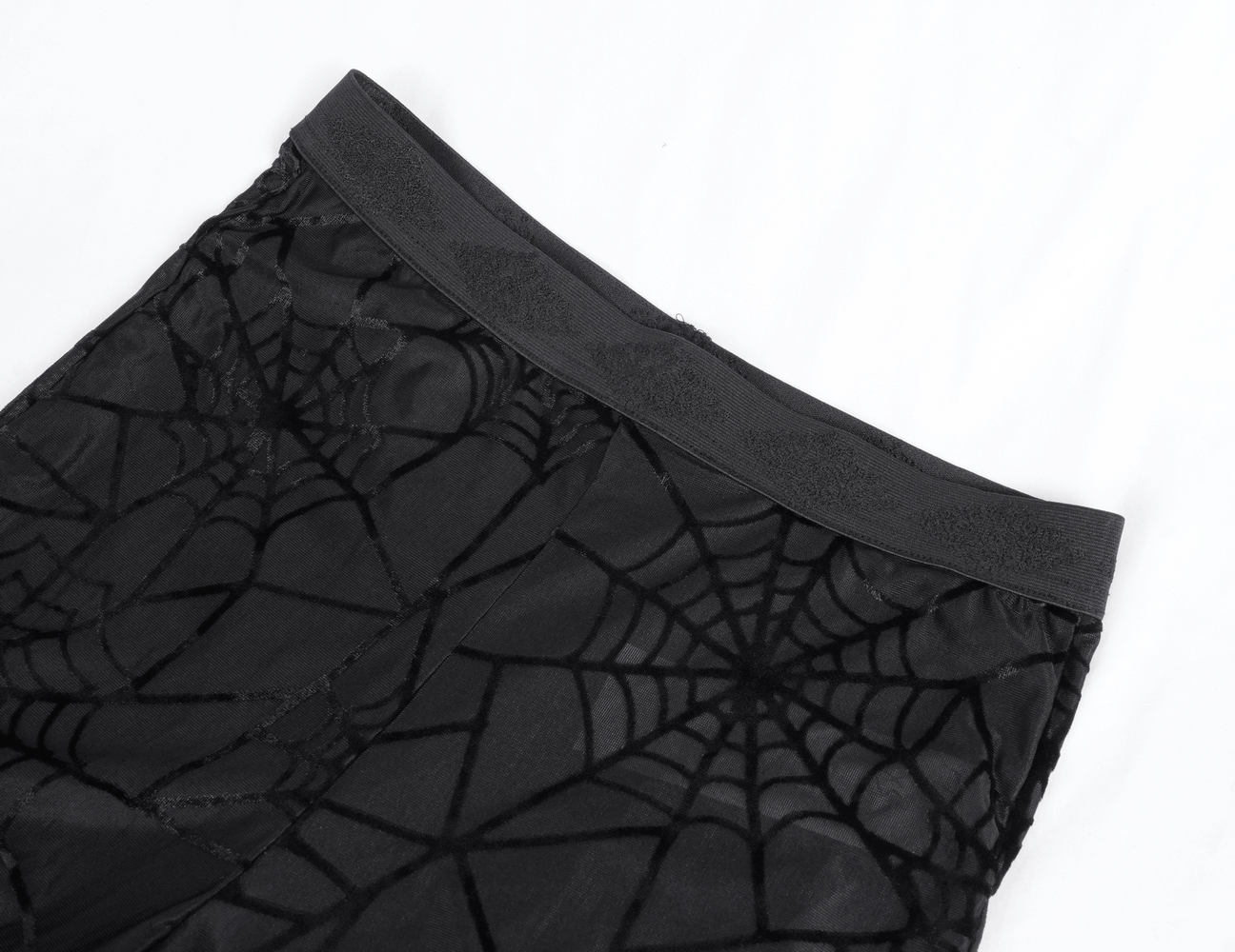 Close-up of black sheer flare pants with spiderweb pattern and high waistband, showcasing gothic elegance.