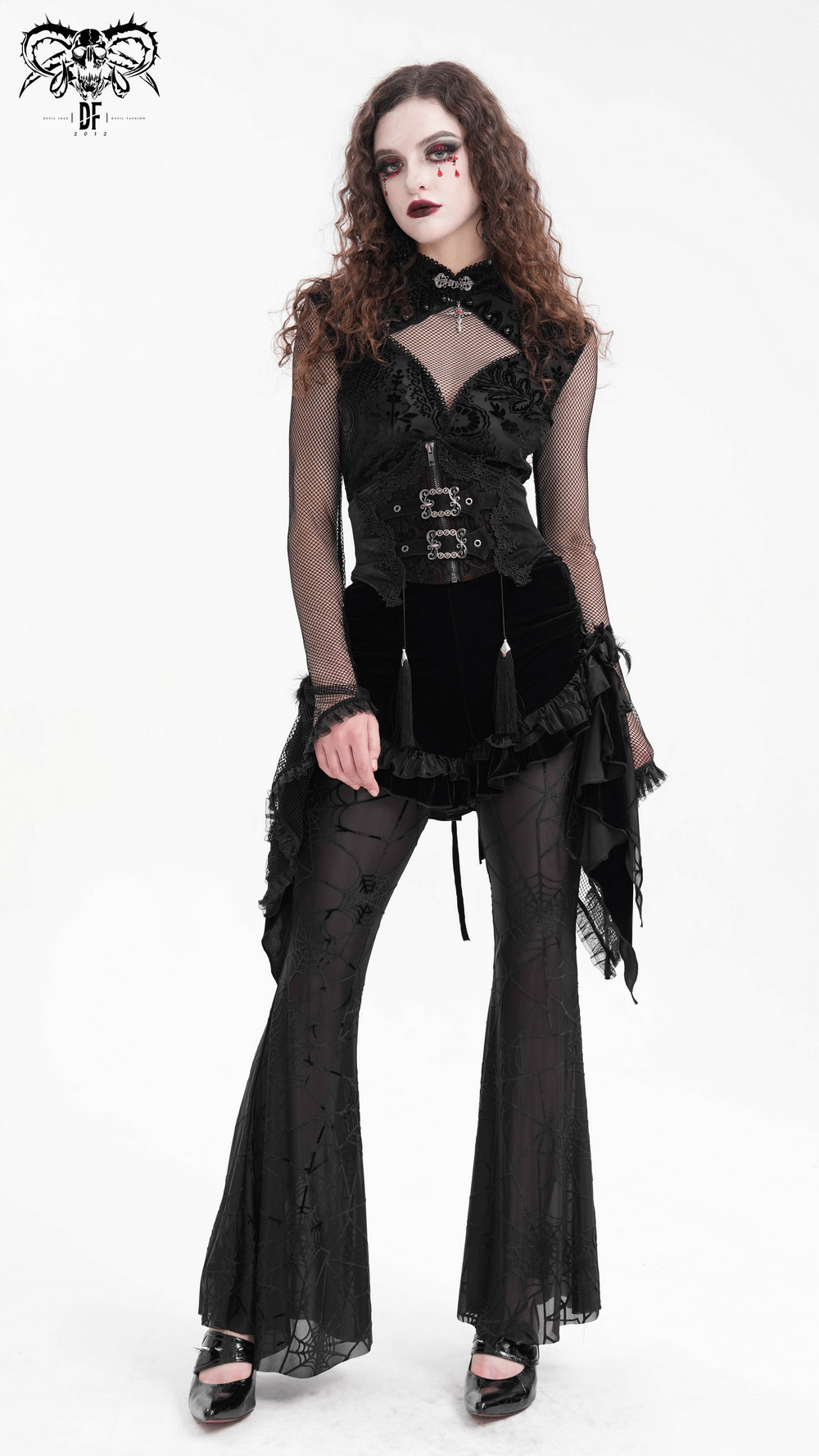 Gothic woman in black sheer flare pants with spiderweb pattern and elegant top, exuding dark elegance.