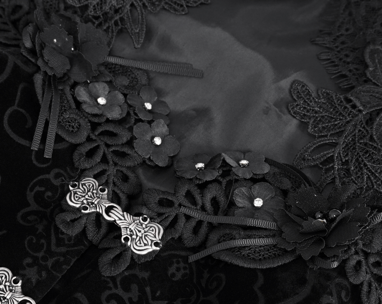 Close-up of intricate black lace detailing with floral embellishments and metallic accents.