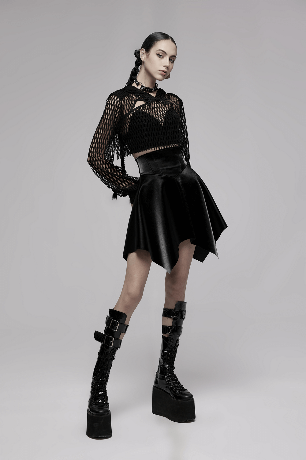 Trendy model wearing a black sheer mesh crop top hoodie with a black skirt and chunky platform boots.
