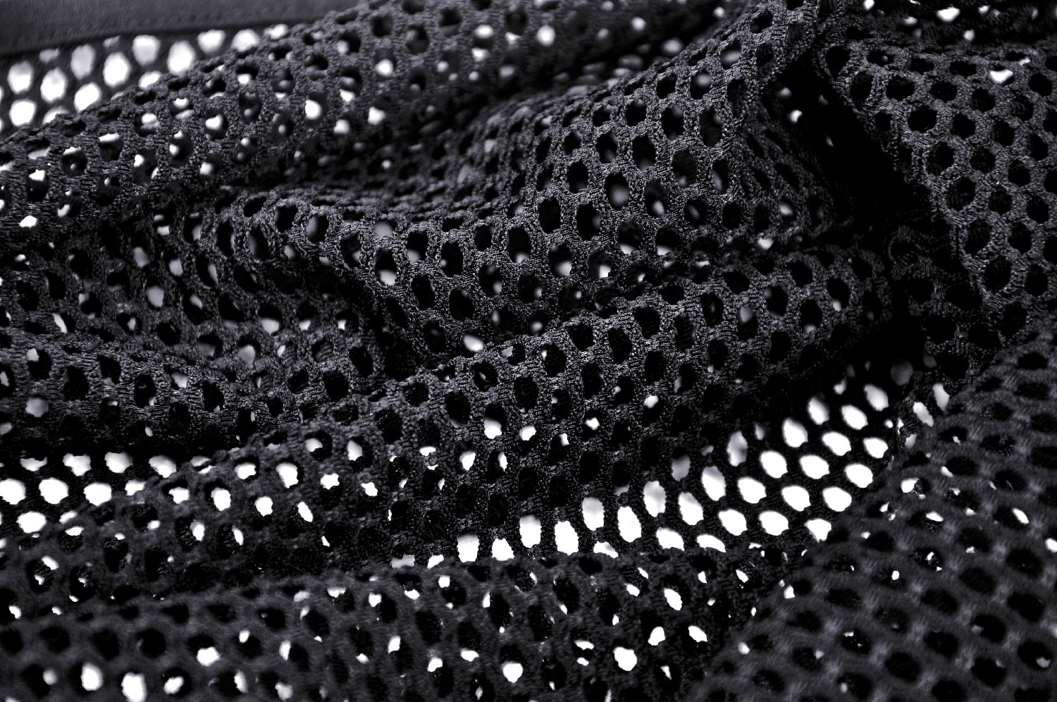 Close-up of black sheer mesh fabric showcasing a fishnet pattern, perfect for edgy fashion styles.