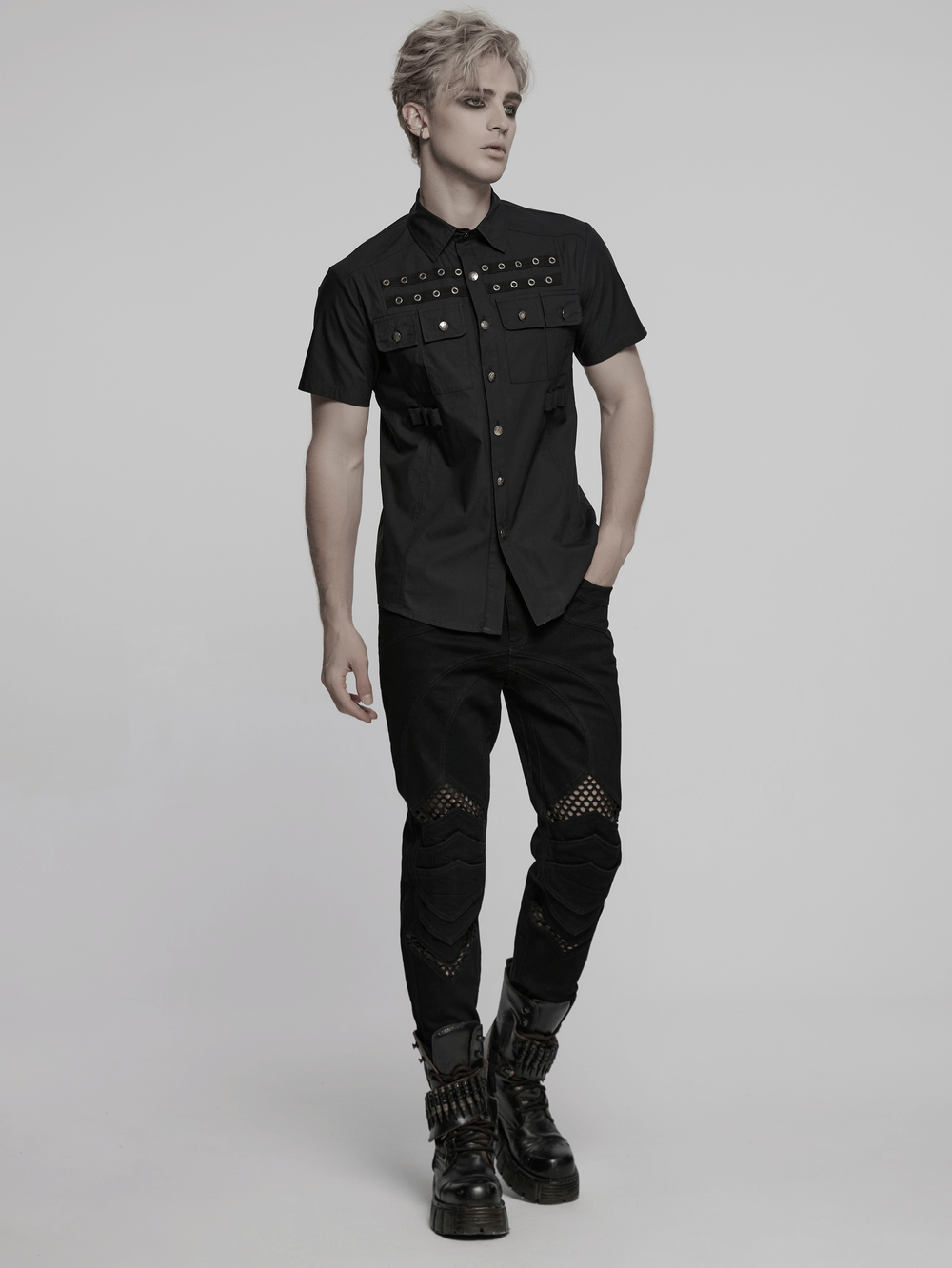 Man wearing a black short sleeve punk shirt with eyelet detail, styled with edgy pants and boots.