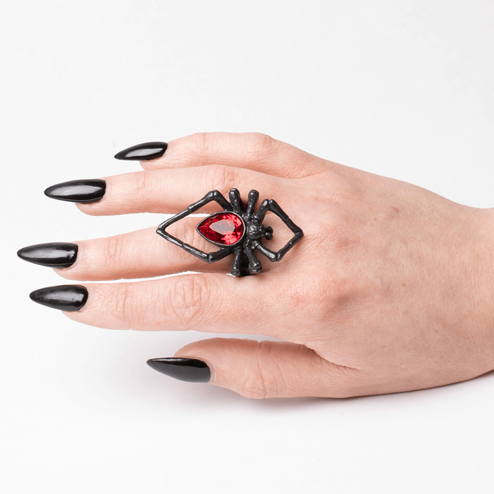 Gothic black spider ring with blood-red crystal on model's hand, showcasing alternative fashion and occult style.