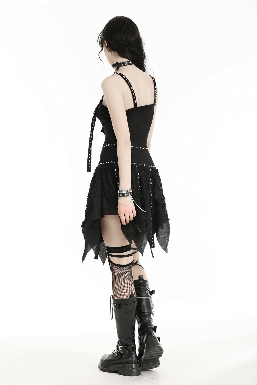 Back view of a model wearing a black studded layered asymmetrical gothic skirt, paired with stylish accessories and lace-up boots.