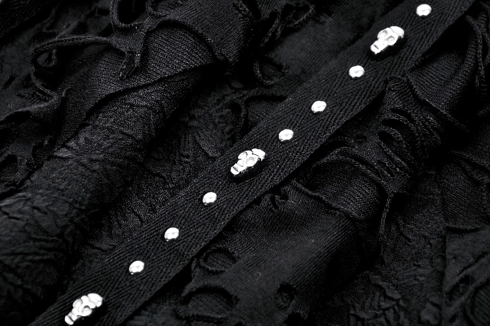 Close-up of black fabric with studded skull details, showcasing gothic elegance in a layered skirt design.