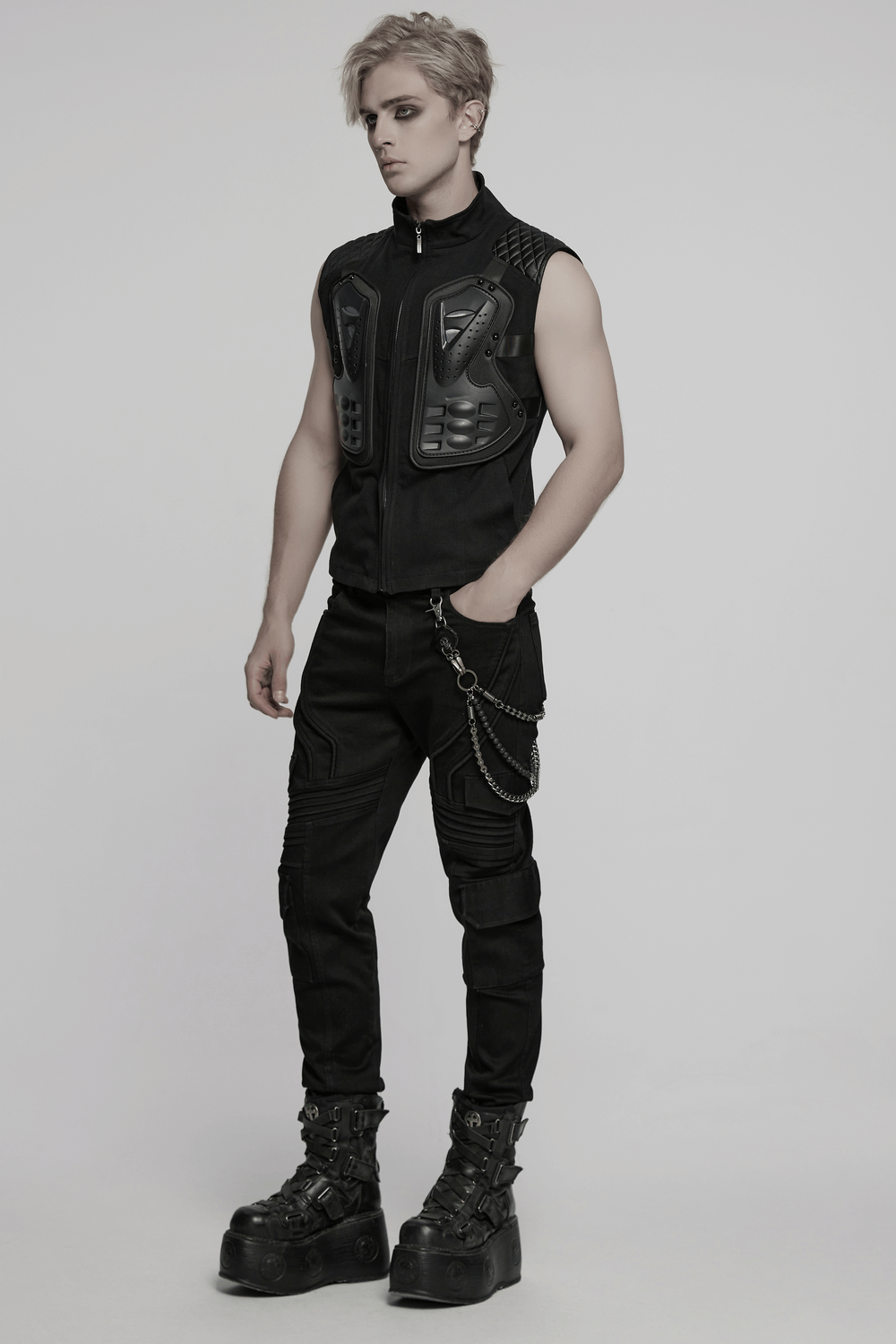 Model wearing a black tactical vest with 3D rubber armor panels, paired with stylish black cargo pants and chunky boots.