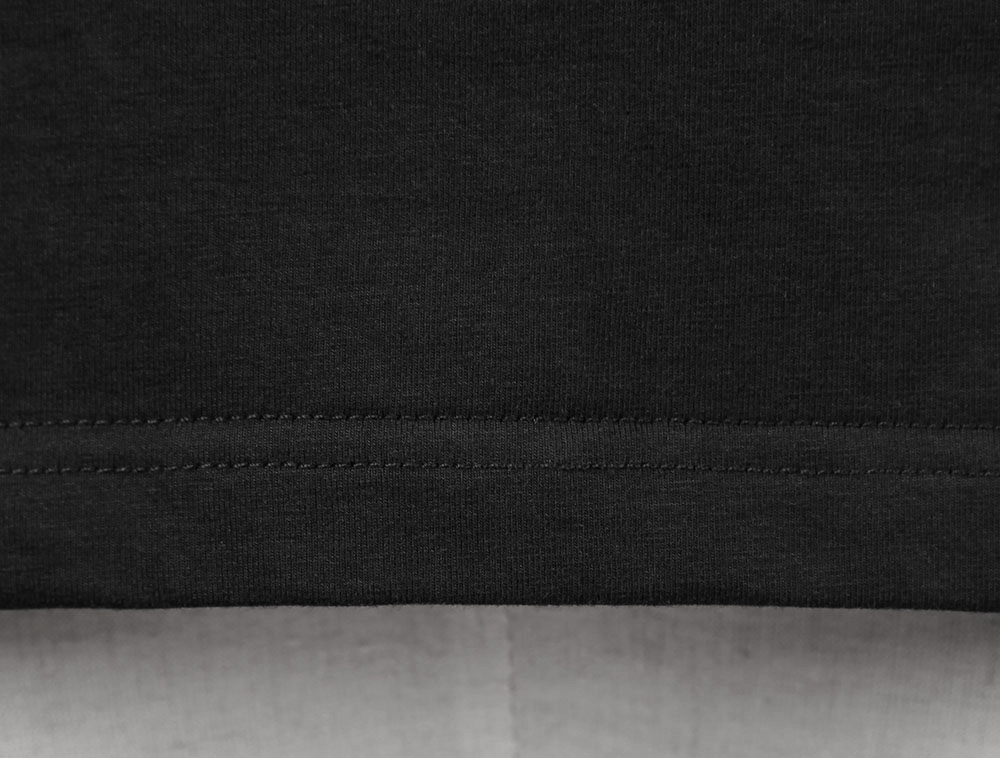 Close-up of the hem detail on a black tank top showcasing smooth stitching and soft fabric texture.