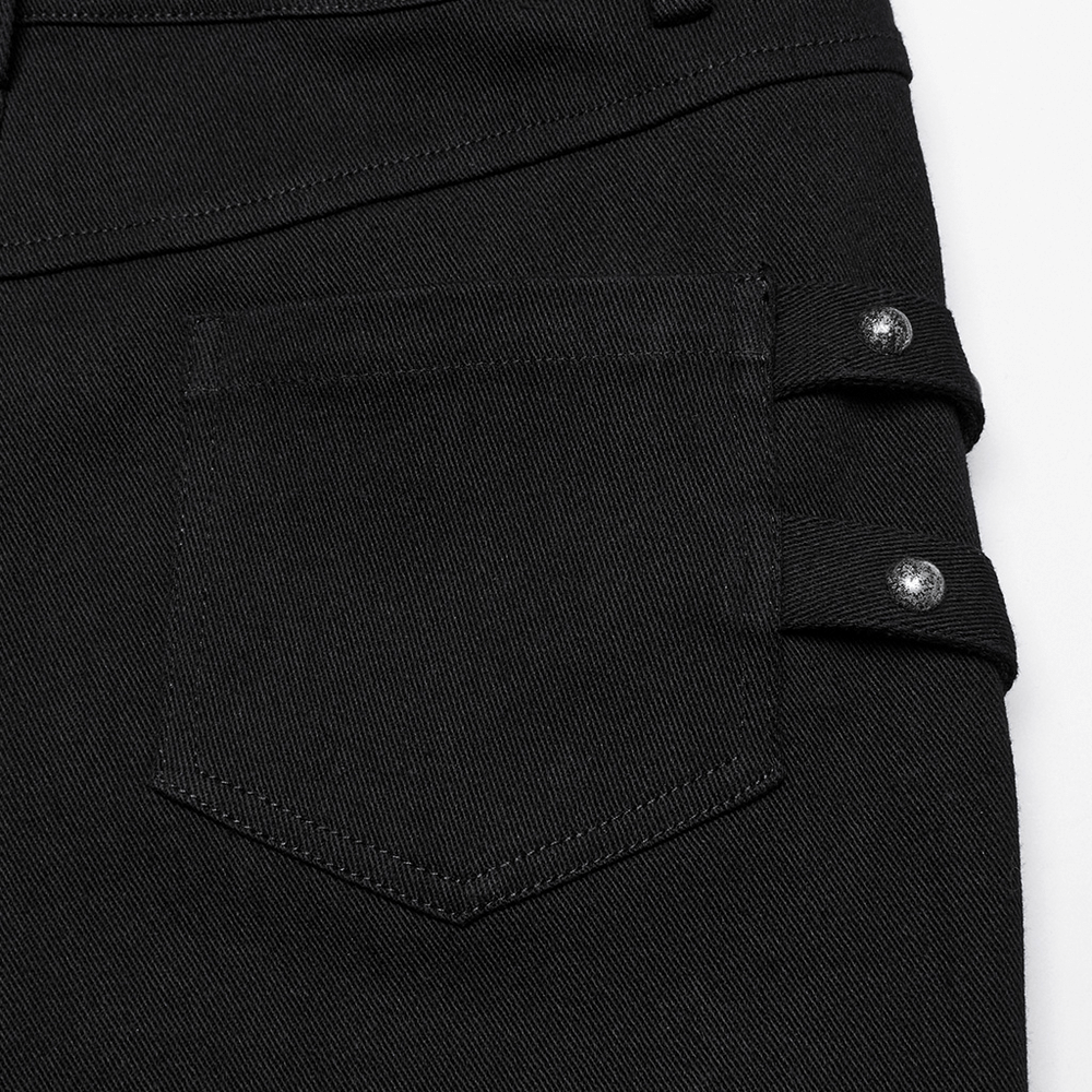 Close-up of black techwear trousers featuring rubber patch details and snap closures on the back pocket.