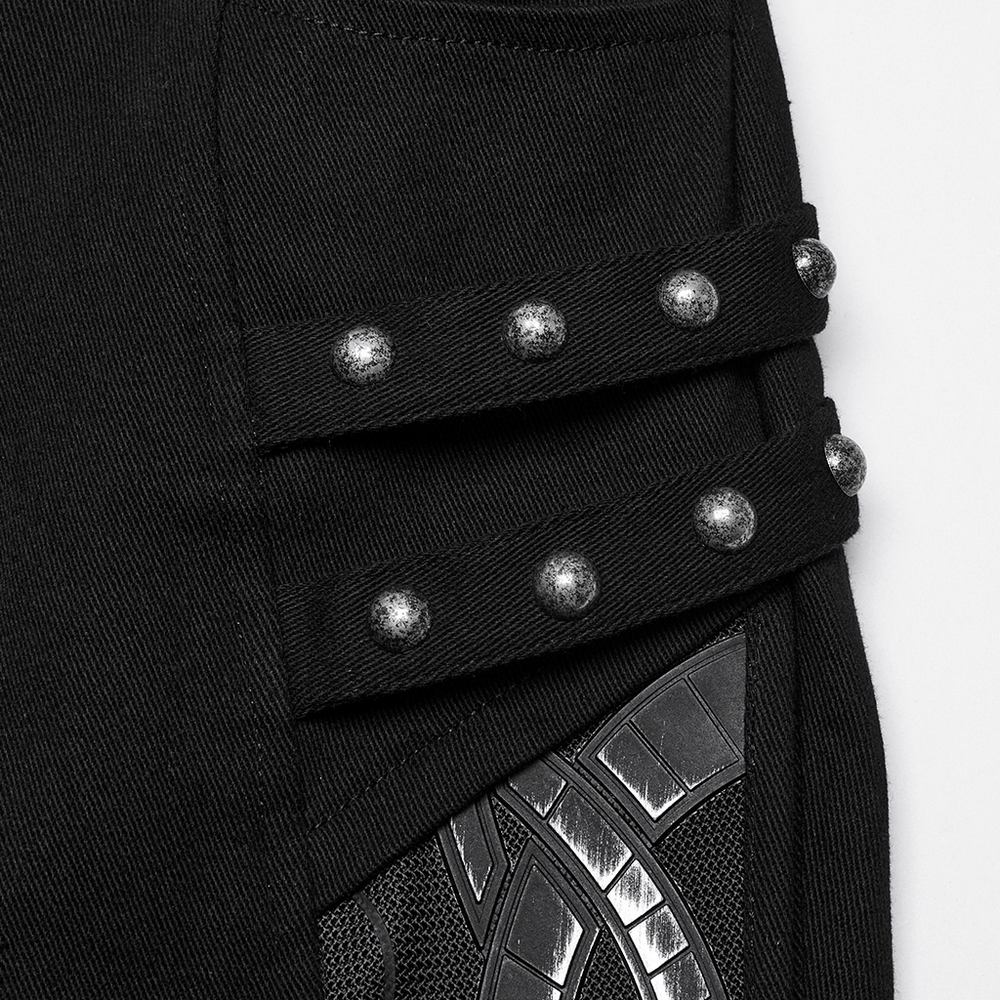 Close-up of black techwear trousers featuring rubber patch details and unique studded straps.