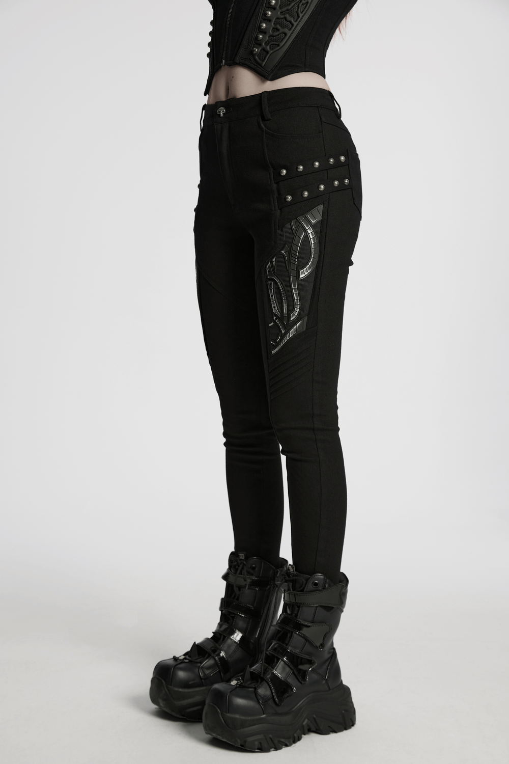 Black techwear trousers featuring rubber patch details, stylishly paired with trendy chunky boots.