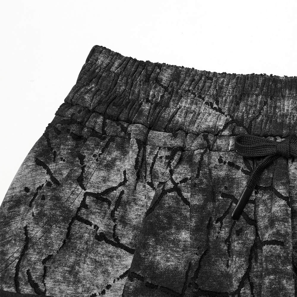 Close-up of black tie dye drop crotch pants featuring eyelet straps and a comfortable elastic waistband.