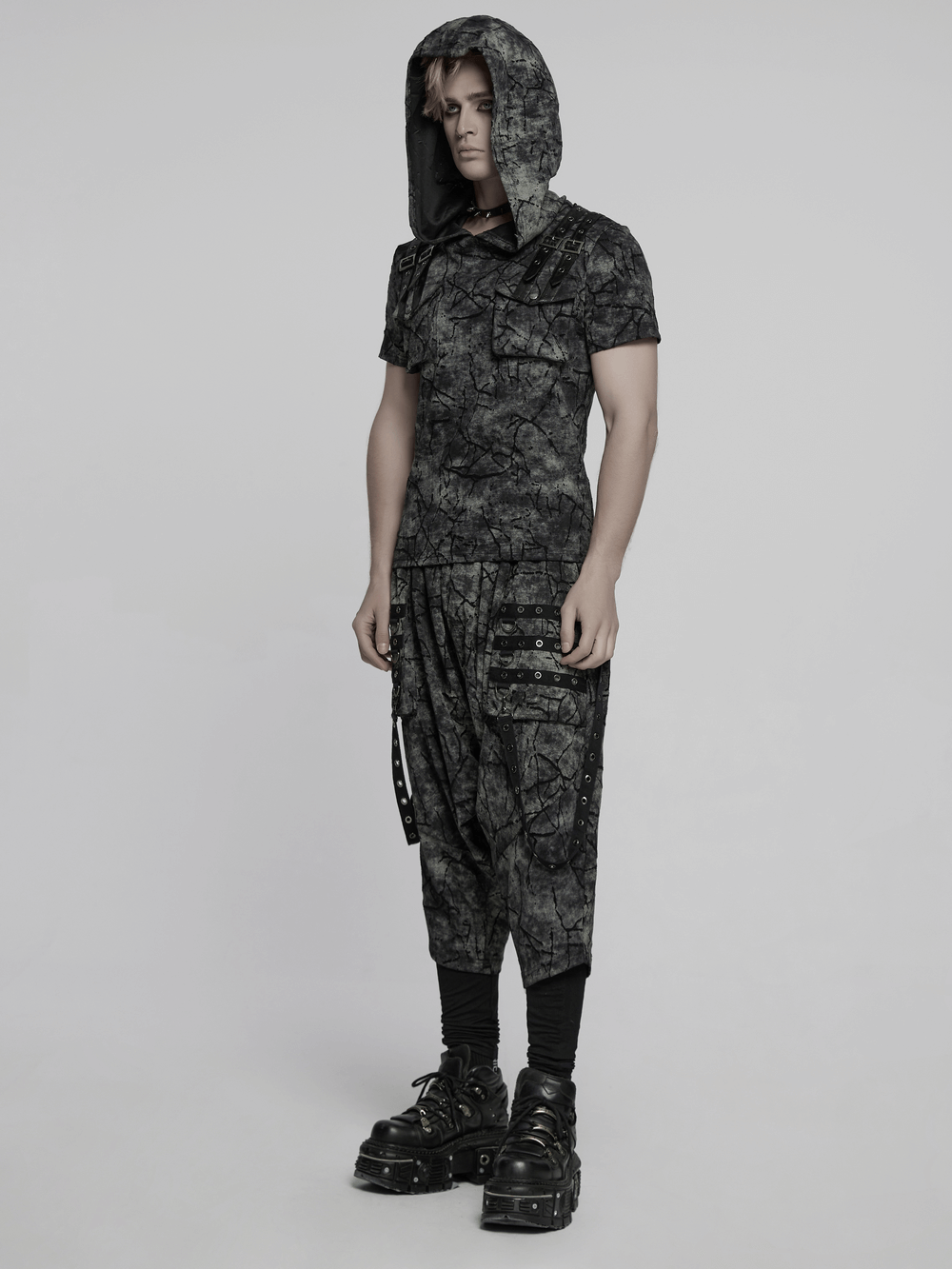 Model wearing black tie dye drop crotch pants with eyelet straps and a matching hooded top.