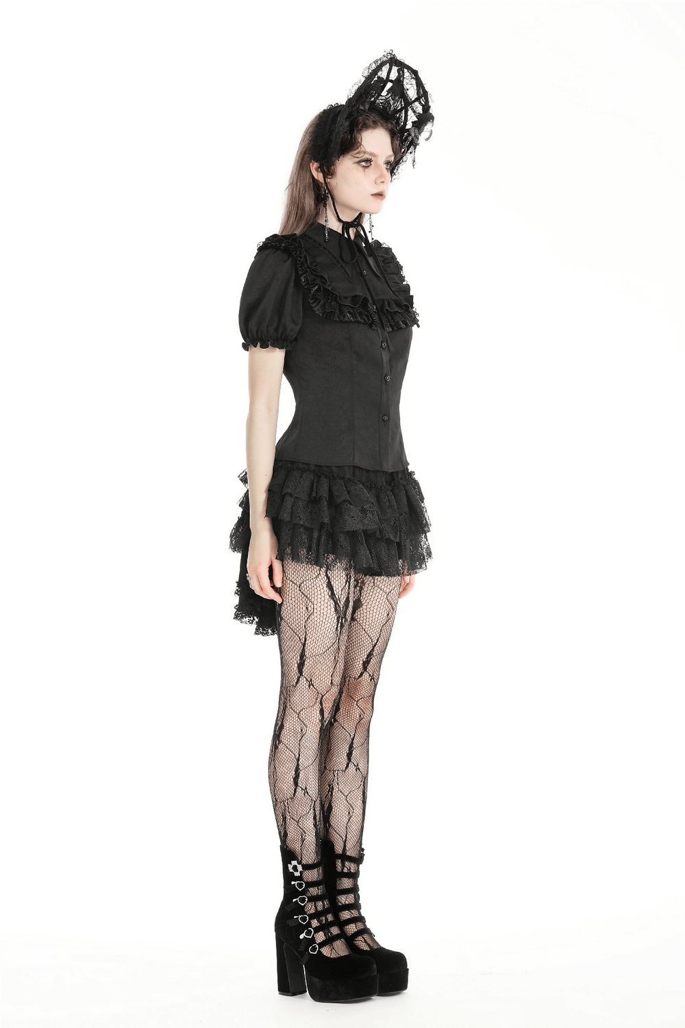 Model in a black ruffled dress with mesh stockings and high-heeled boots, showcasing edgy fashion style.