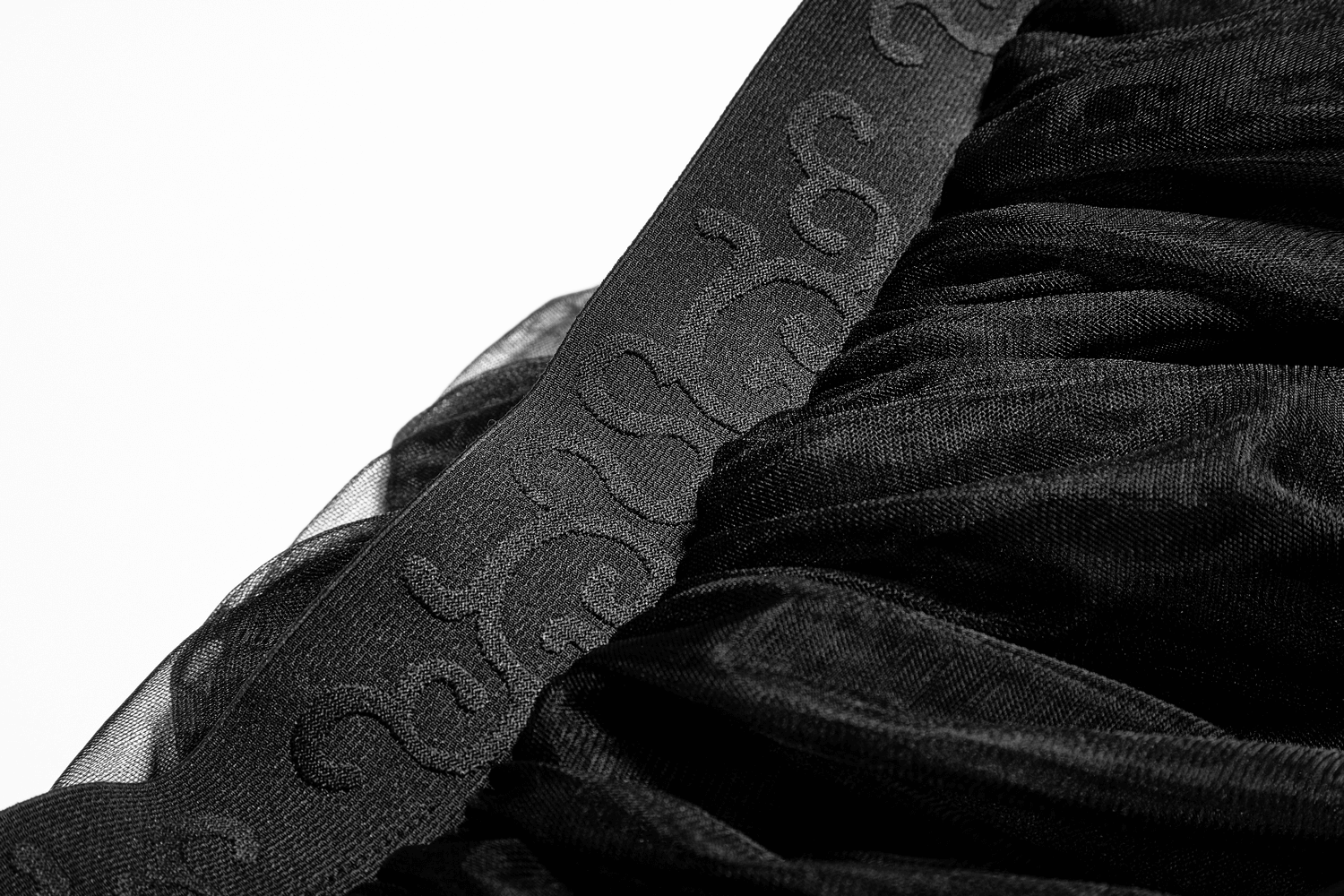 Close-up of black tulle fabric with intricate lace detailing for a gothic wedding dress.