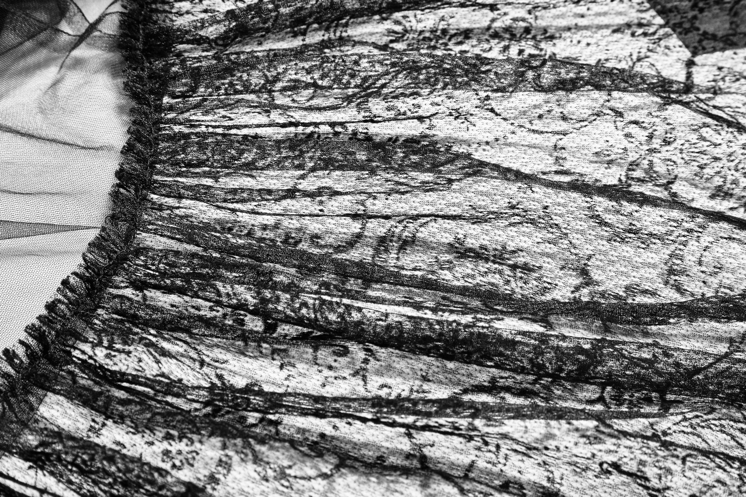 Close-up of black tulle fabric with intricate lace details, showcasing the romantic texture of a gothic wedding dress.