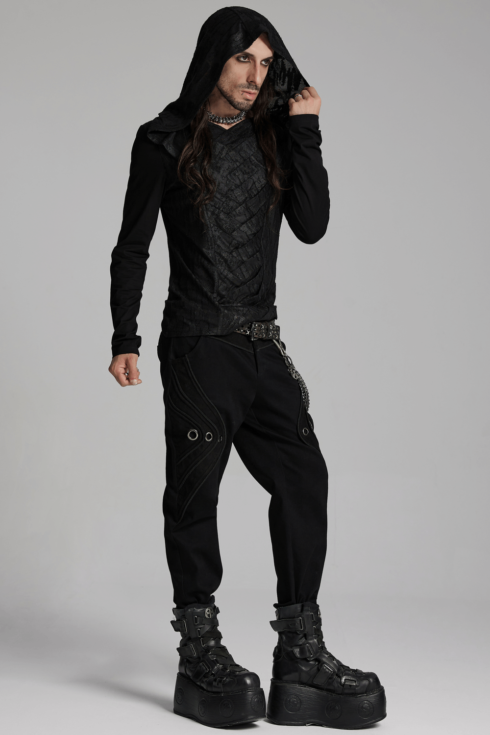 Man in black punk-inspired outfit featuring 3D patchwork denim pants and oversized boots, exuding edgy style.