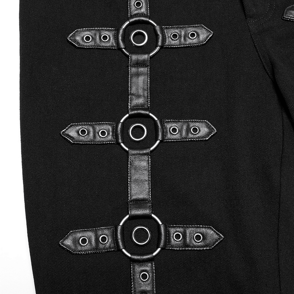 Close-up of black twill punk pants featuring metal rings and adjustable straps for an edgy, innovative look.