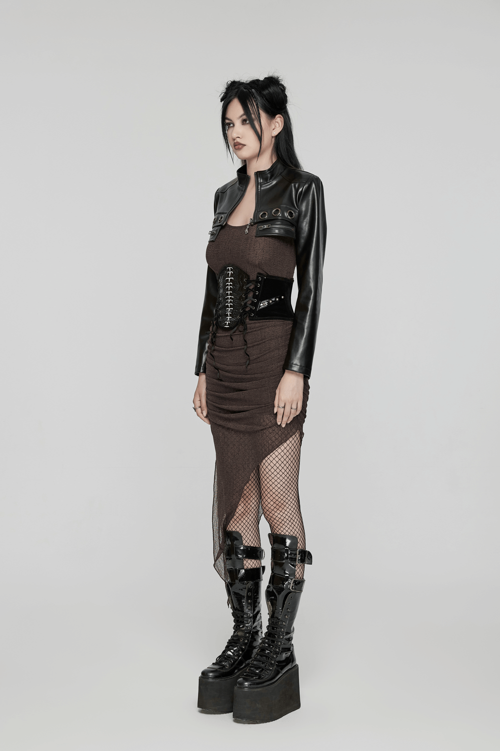 Gothic model wearing a black velvet and patent leather corset belt with rivets and lace-up back, showcasing edgy style.