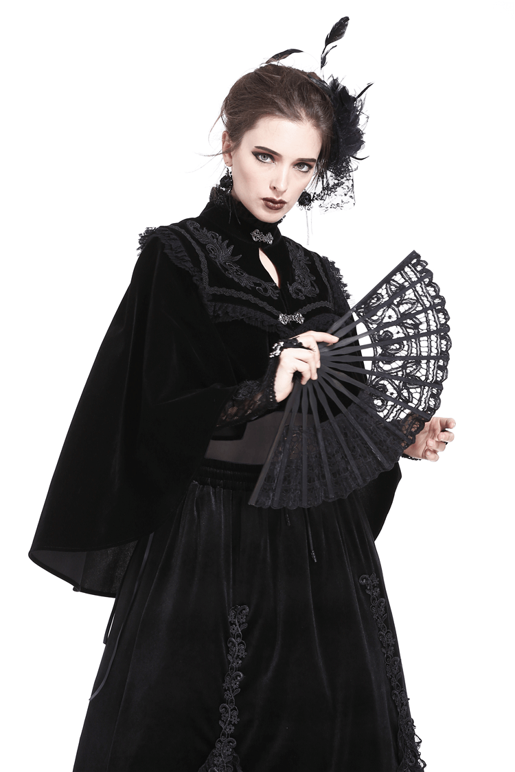 Elegant black velvet capelet with embroidered lace collar, worn with a black fan and theatrical makeup.