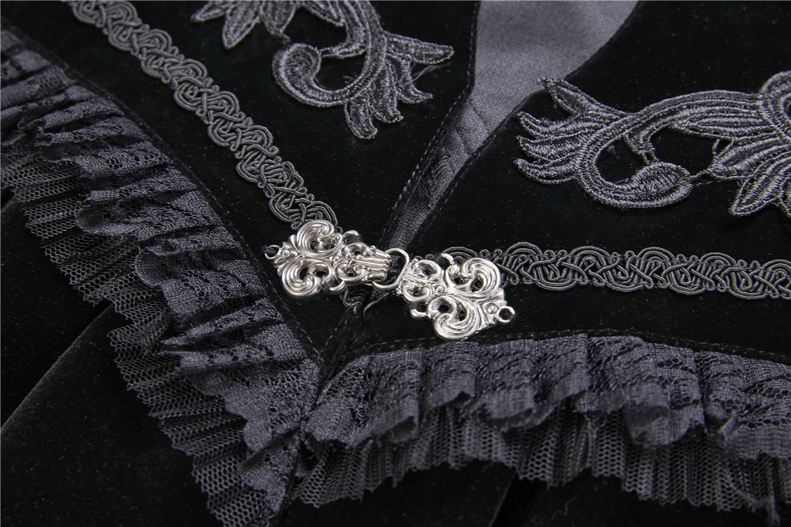 Close-up of a black velvet capelet featuring an embroidered lace collar and ornate silver clasp.
