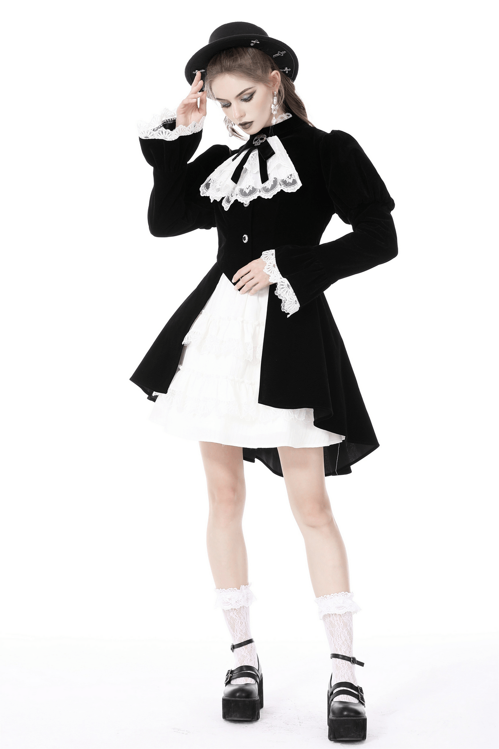 Black velvet gothic coat with white lace collar and cuffs worn over a white dress, stylishly paired with a small hat.