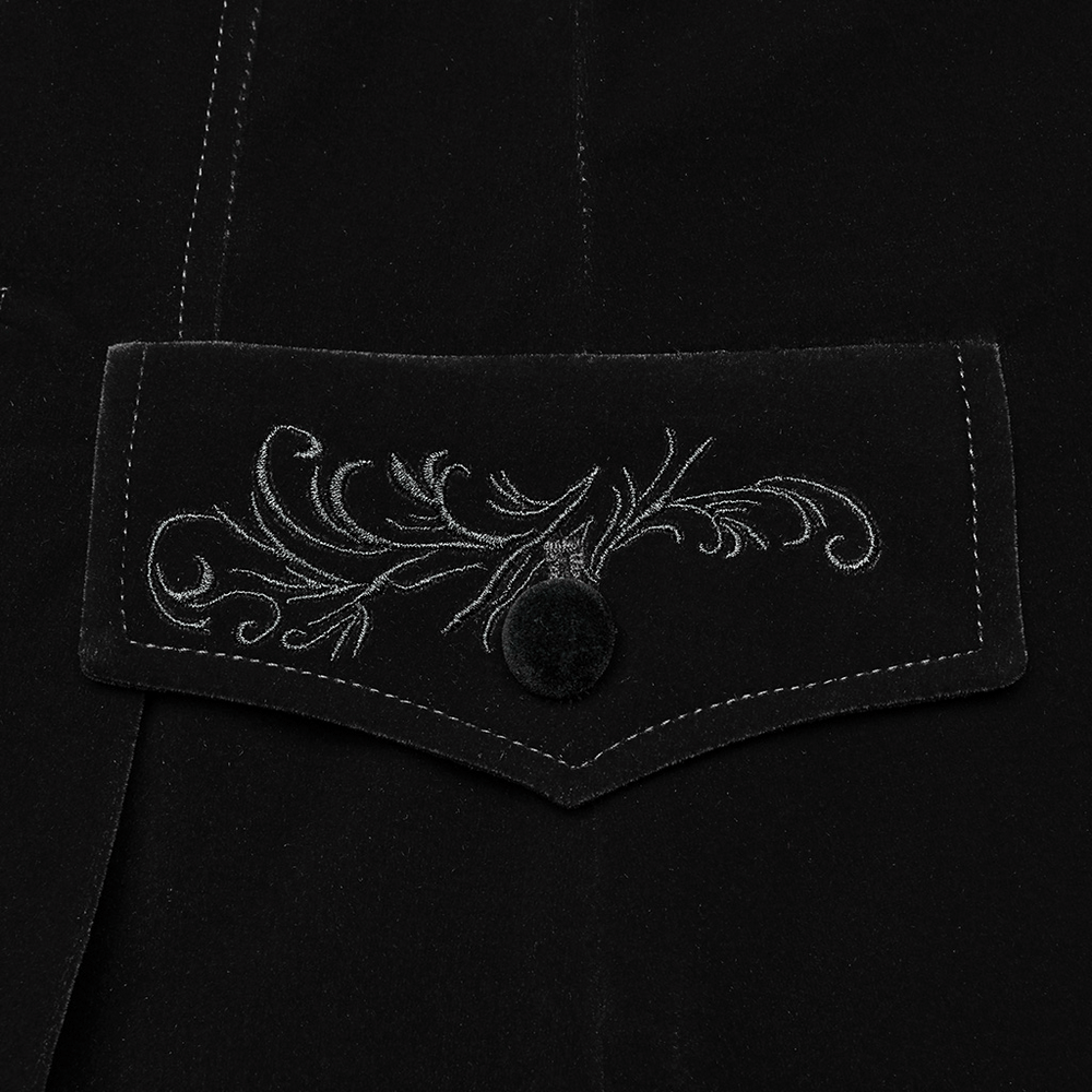Close-up of embroidered pocket cover on black velvet gothic tailcoat, showcasing intricate floral design and button detail.