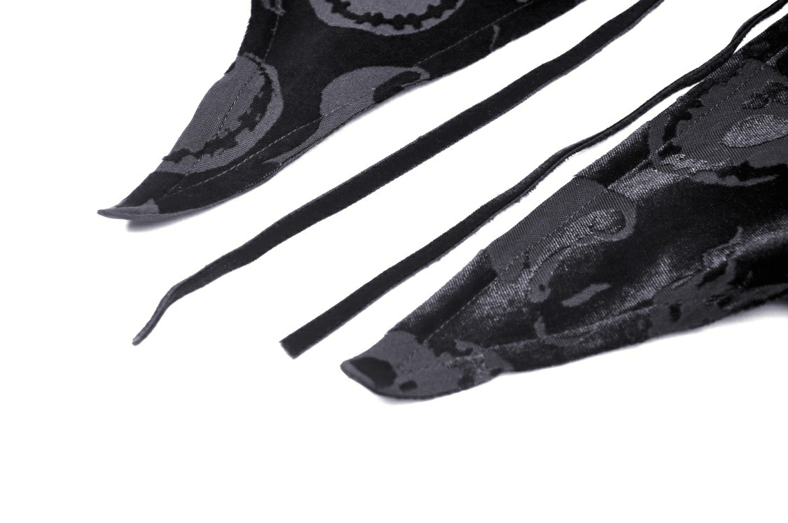 Close-up of black velvet cape edges and ties with intricate skull print design.
