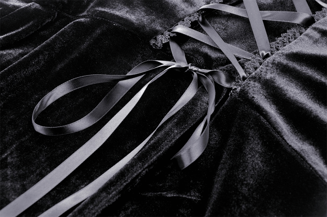 Close-up of black velvet hooded cloak highlighting satin ribbons and luxurious fabric.
