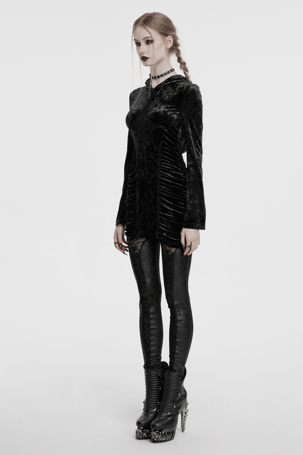 Model wearing a black velvet lace cross dress with hood, side waist pleats, and edgy black leggings.