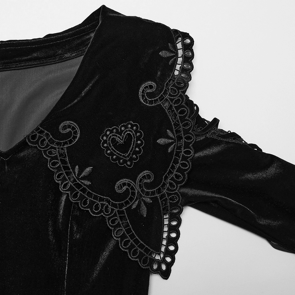 Close-up of black velvet dress with gothic heart applique and intricate lace detailing on flared sleeves.