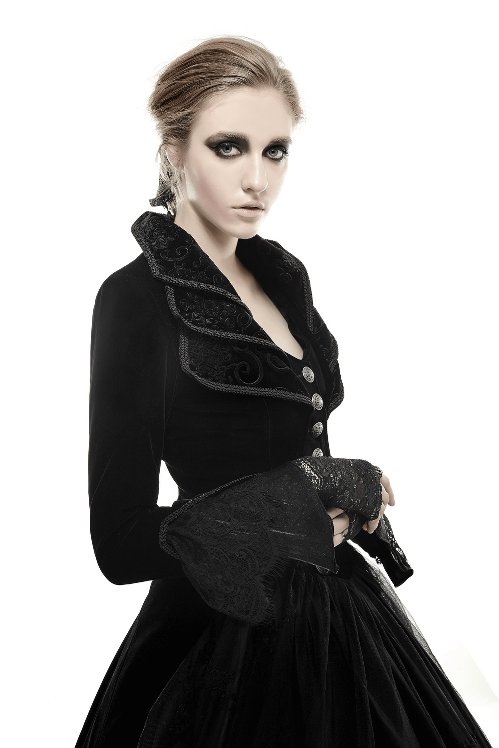 Elegant model in a black velvet gothic trench coat with cascading collar and intricate details.