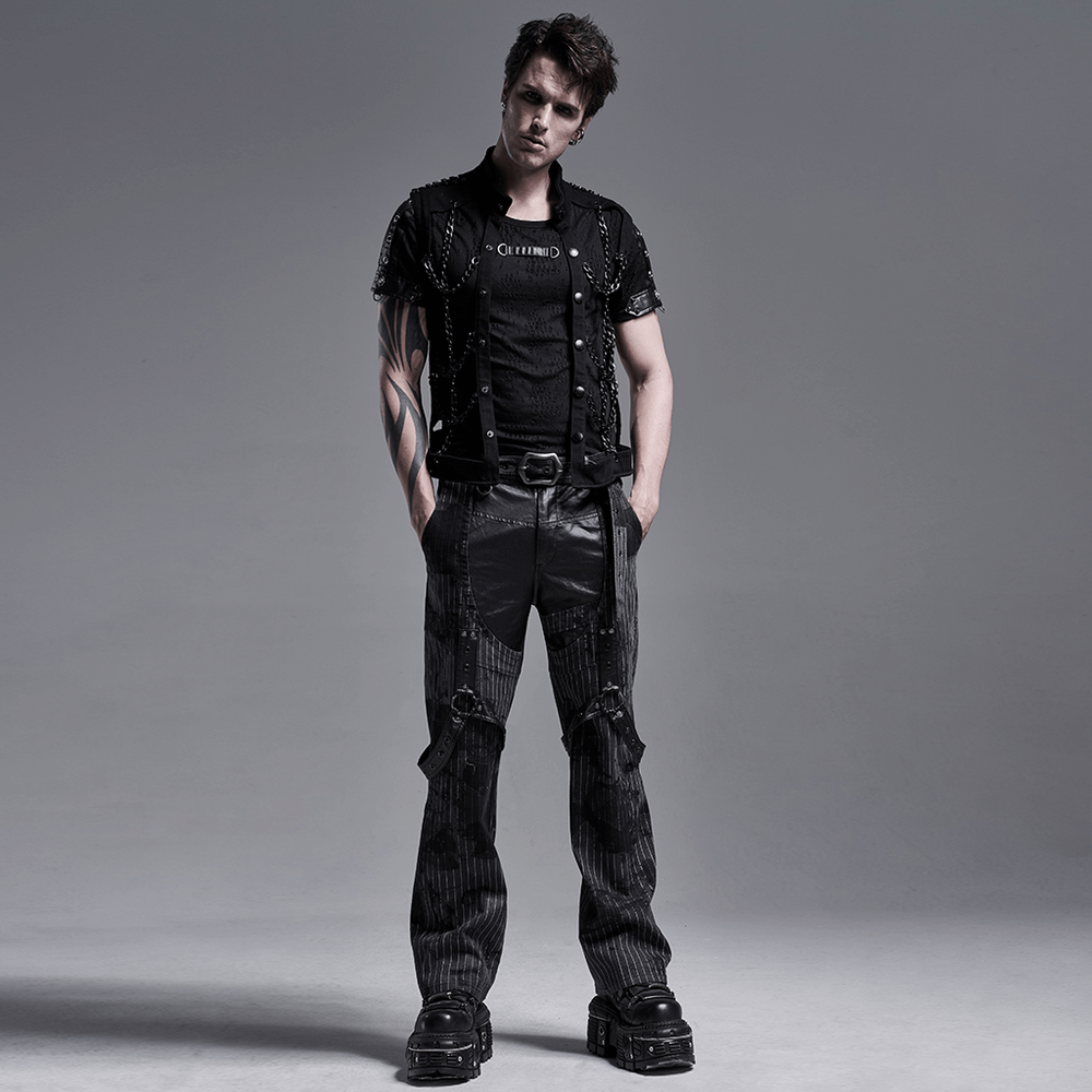 Stylish man in a black punk vest and pants, showcasing edgy fashion with chain and hollow-out details.