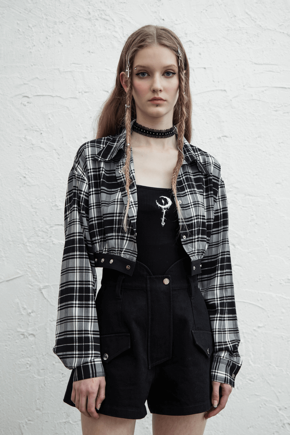 Model wearing a black and white plaid punk gothic outfit with detachable elements and edgy accessories.