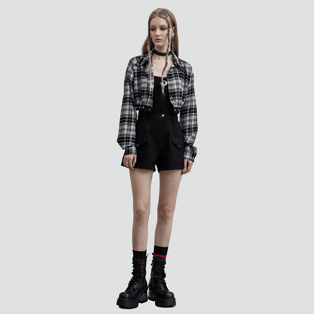 Model wearing a black and white plaid detachable dress with edgy buckle accents and combat boots.