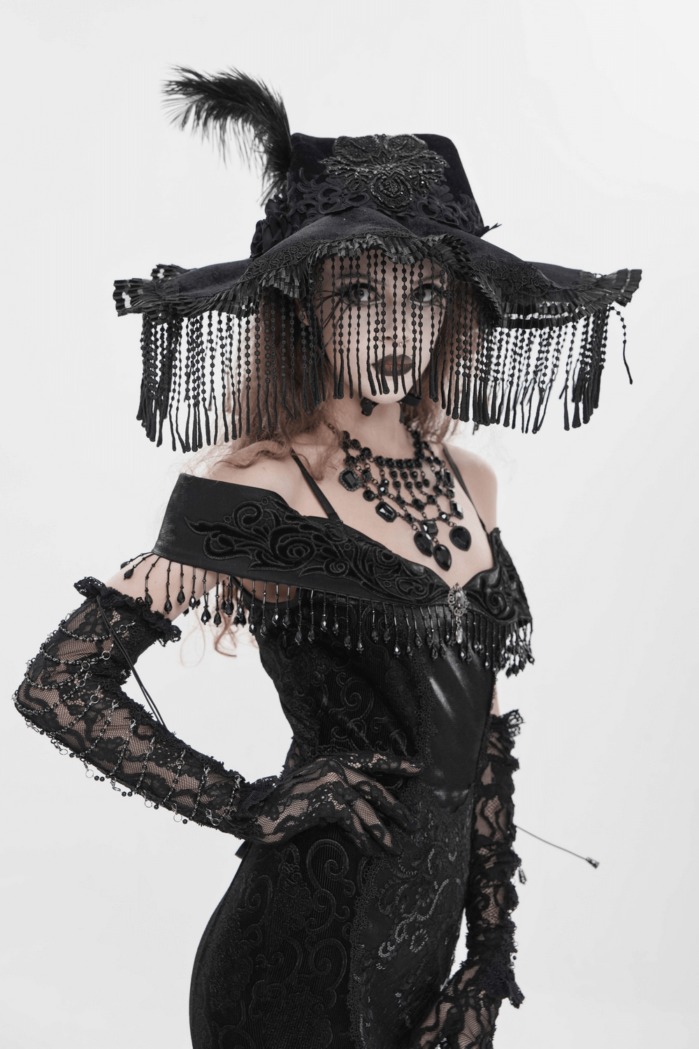 Black Witch Hat with Lace Fringe and Feather Detail worn elegantly by a model in gothic attire.